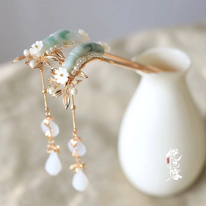 Yulan traditional Chinese jade tassel hair pin with gold-toned metal frame white flower embellishments and teardrop pendant displayed on a linen tabletop