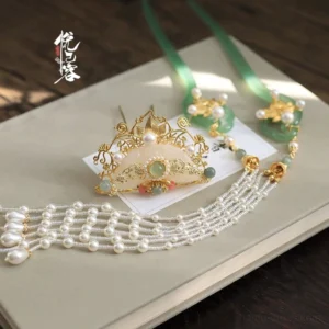 Complete Yun Yan Ji Hanfu hair accessories displayed on a vintage notebook, featuring gold filigree, white and green jade-toned beads, pearl tassels, and elegant silk-colored ribbon details