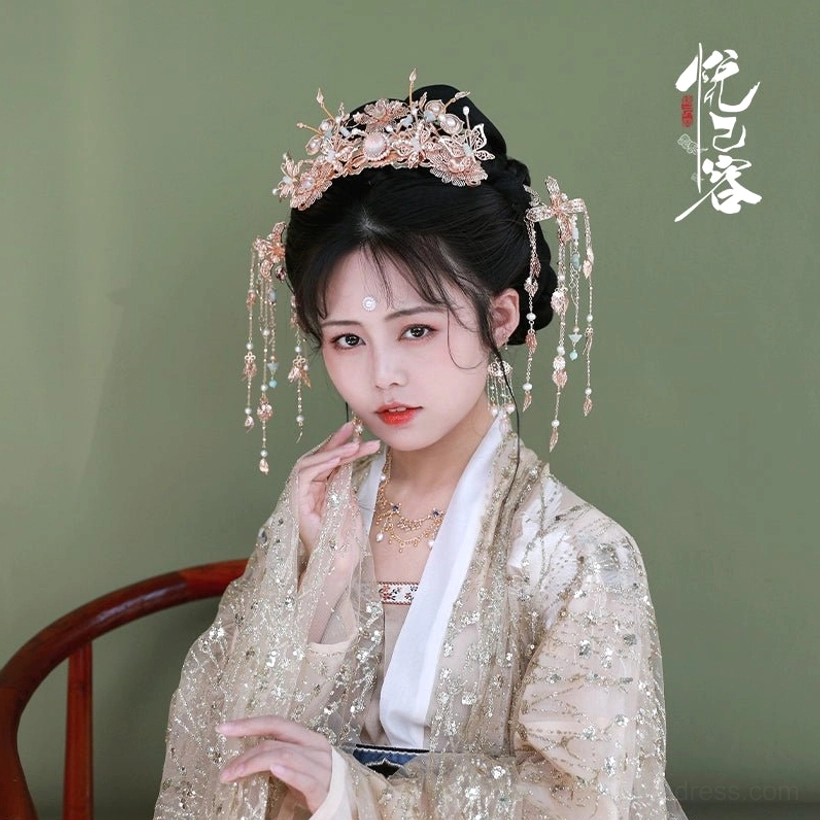 Woman styling a Yunhuali traditional Chinese hair crown high on an elegant updo with matching dangling side ornaments