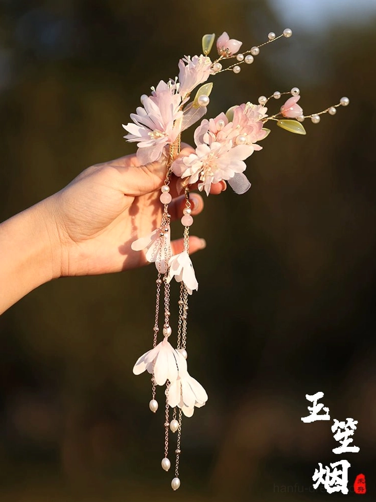 Close-up handheld view of Yuyue Hanfu hair accessory set featuring pink silk flowers faux pearl branches gold tassels and white petal pendants