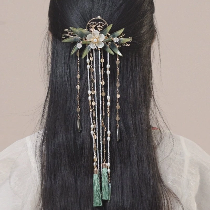 Back view of a model wearing the Zhuqin Chinese tassel hairpin with white jade-like flowers, green bamboo ornaments, layered beaded tassels, and dark green pendants with light Hanfu
