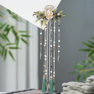 Oblique overhead view of the Zhuqin vintage Chinese hairpin with gold-toned base, floral decorations, green leaves, beaded tassels, and dark green pendant accents