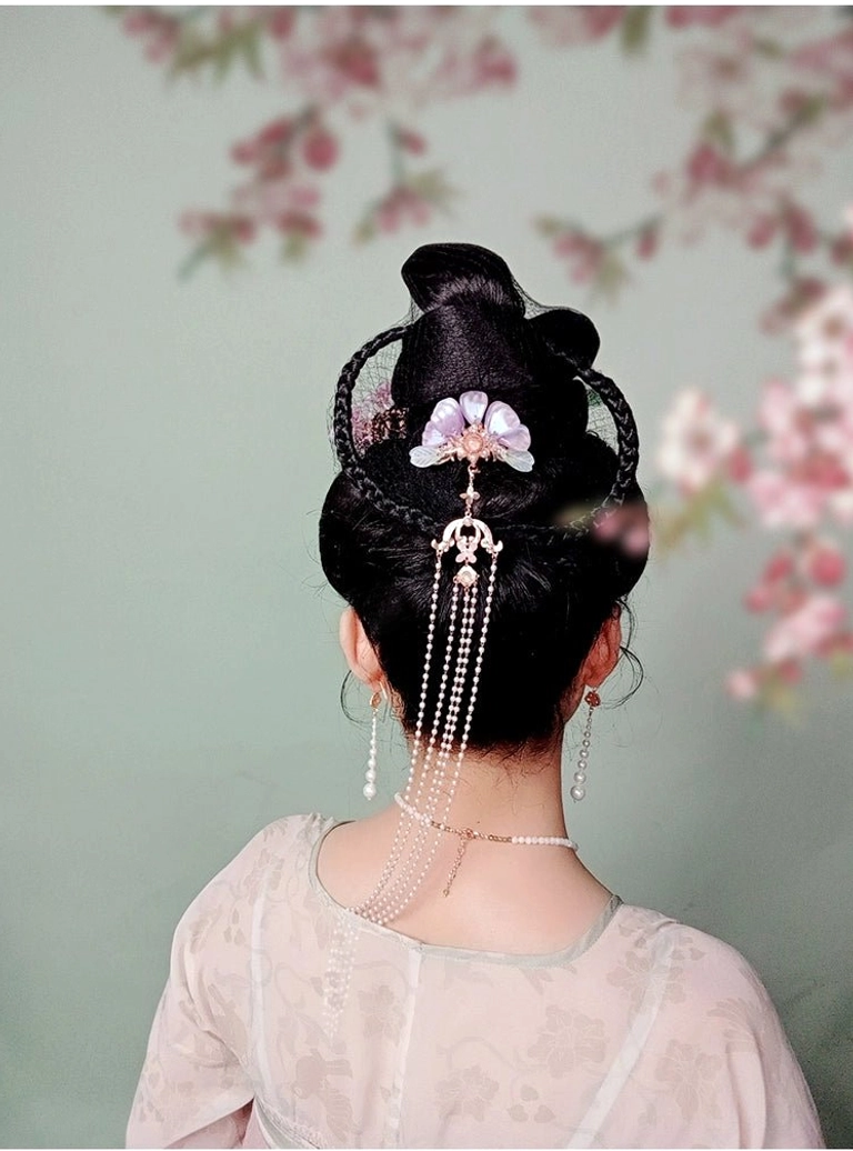 Zixuan traditional Chinese hair pin worn in a coiled ancient hairstyle with pink Hanfu clothing floral backdrop pearl tassel and matching Chinese jewelry