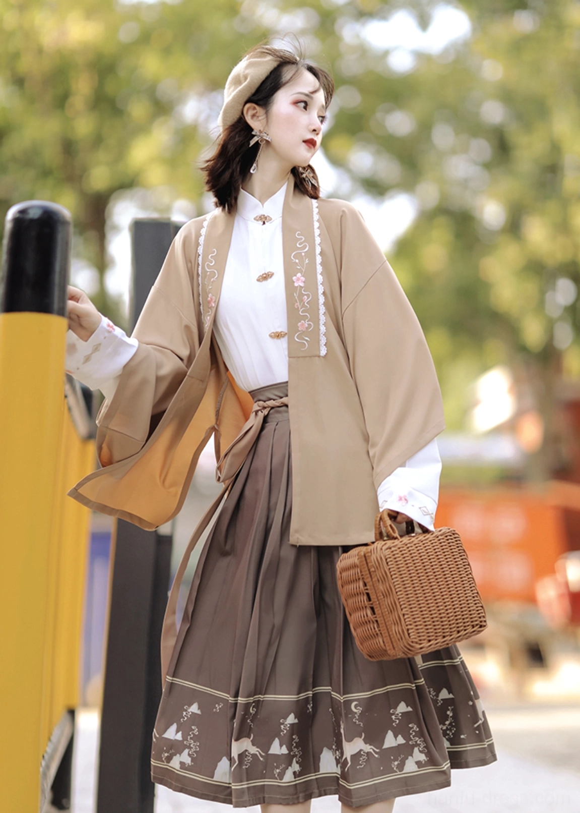 Side view of khaki daily modern Hanfu outfit with embroidered outer cardigan, white collared shirt, brown printed pleated skirt and woven handbag