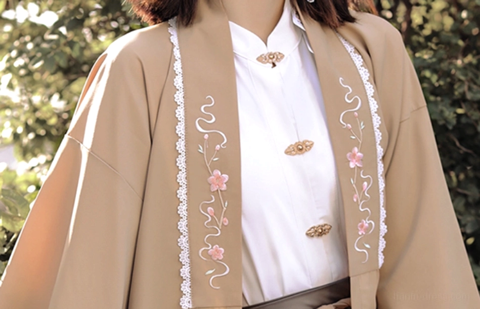 Close-up of khaki modern Hanfu cardigan with pink floral vine embroidery, white trim, stand-collar inner shirt and brass Chinese knot buttons