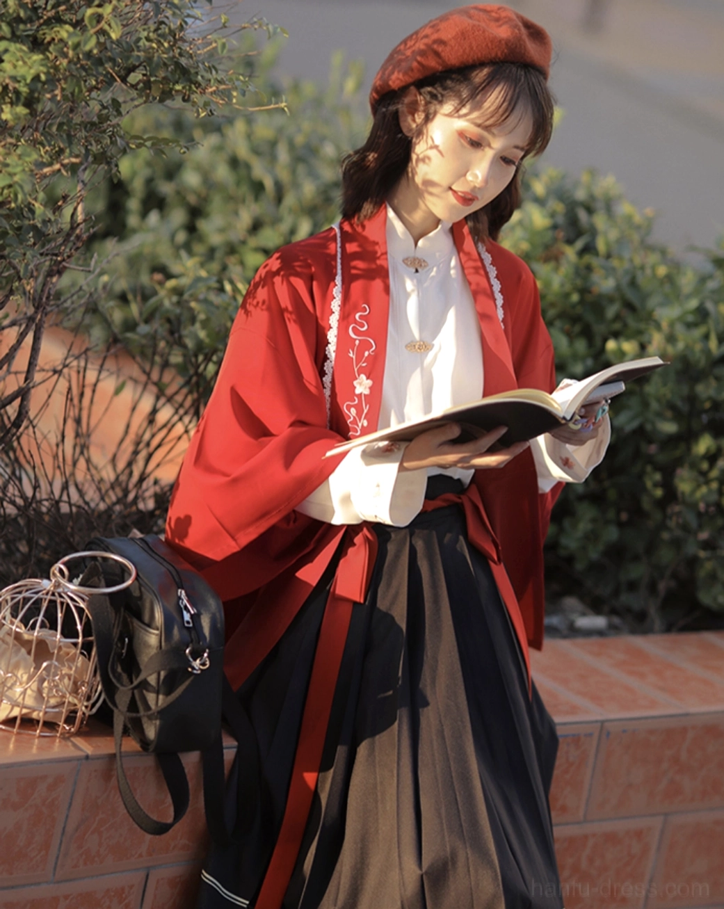 Side view of red embroidered modern Hanfu outfit featuring floral cardigan, white stand-collar shirt, printed pleated midi skirt and matching beret
